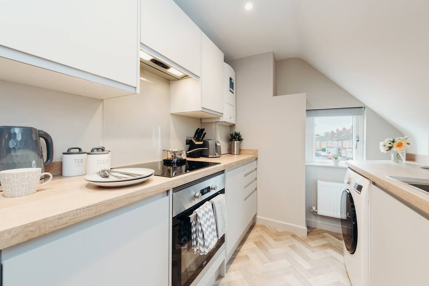 A modern kitchen with a built-in oven, a dishwasher, and a window providing a view of the outside.