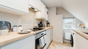 A modern kitchen with a built-in oven, a dishwasher, and a window providing a view of the outside.