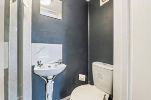Ein Badezimmer mit einem weißen Waschbecken, einem Spiegel und einer Toilette.