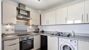 Una cucina moderna con elettrodomestici in acciaio inossidabile, lavastoviglie e lavatrice integrata.