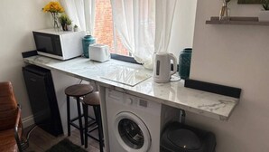 Uma cozinha compacta com máquina de lavar, micro-ondas e torradeira.