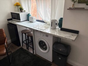 A compact kitchen with a washing machine, a microwave, and a toaster. - #194 Smart Coventry Studio | Ideal for 2 (West Midlands)