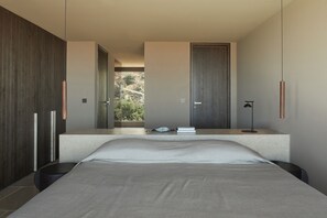 Een moderne slaapkamer met een groot bed, een nachtkastje en uitzicht op de omgeving.