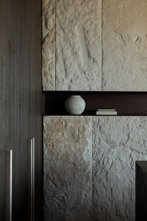 Ein Zimmer mit einer Steinwand, einem Holzschrank und einer Steinskulptur.