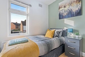 A bedroom with a bed, bedside table, lamp, and a painting on the wall. - #134 Cozy Retreat Close to FarGo Village -Sleeps 7 (West Midlands)