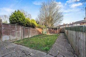 A backyard with a wooden fence, a grassy area, and a stone pathway. - #134 Cozy Retreat Close to FarGo Village -Sleeps 7 (West Midlands)