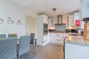 A modern kitchen with white cabinets, a stainless steel range hood, and a built-in oven. - #134 Cozy Retreat Close to FarGo Village -Sleeps 7 (West Midlands)
