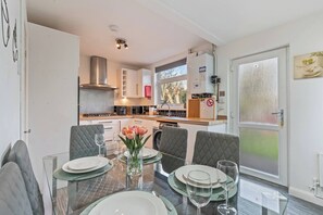 A modern kitchen with white cabinets, a stainless steel range hood, and a built-in microwave. - #134 Cozy Retreat Close to FarGo Village -Sleeps 7 (West Midlands)