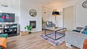 Ein Wohnzimmer mit Flachbildfernseher, Kamin, Couchtisch und Sofa.