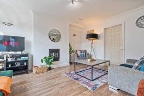 A living room with a flat-screen TV, a fireplace, a coffee table, and a sofa. - #134 Cozy Retreat Close to FarGo Village -Sleeps 7 (West Midlands)