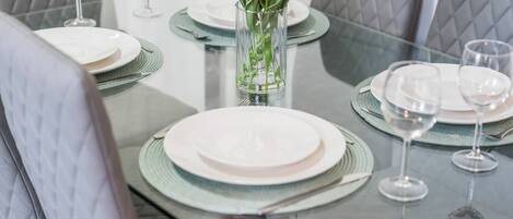 A dining table set with plates, glasses, and a vase with flowers.