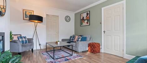 A living room with a sofa, a coffee table, a floor lamp, and a door.