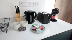 En köksbänk med en kaffebryggare, en brödrost, en mugg och en tallrik med mat.