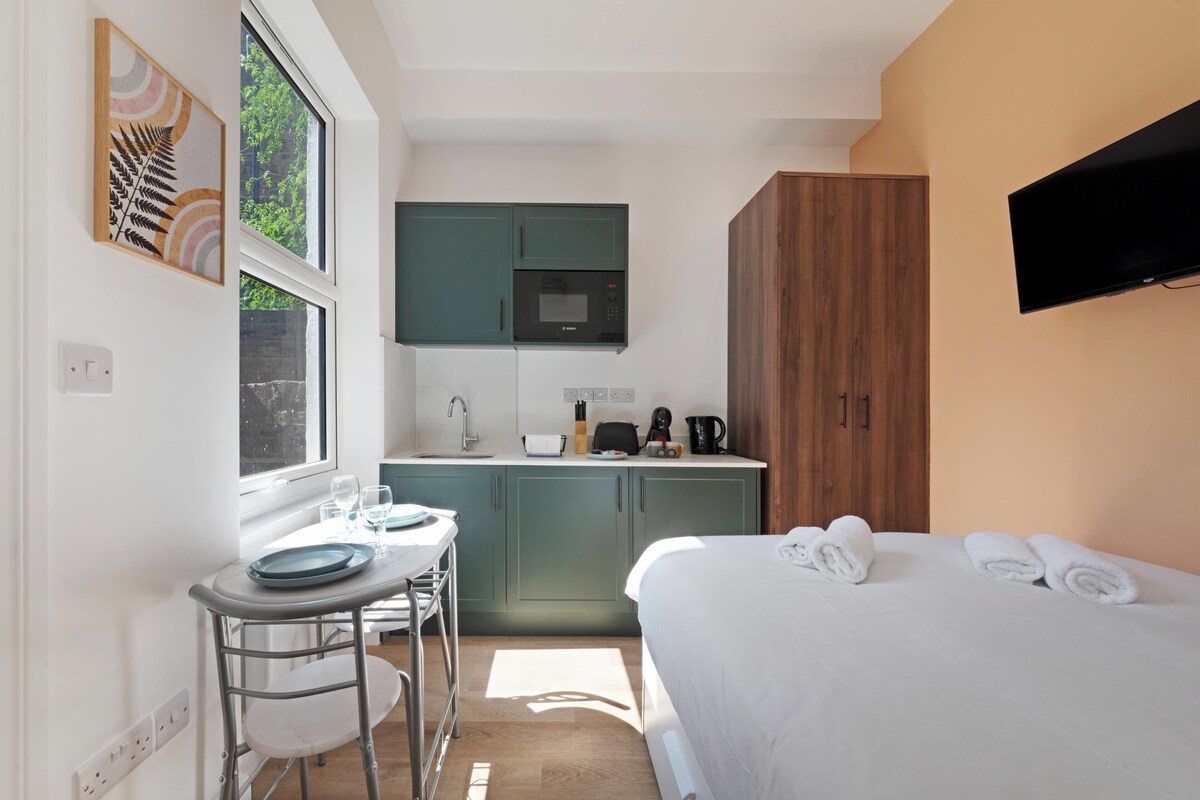 A compact bedroom with a bed, a bedside table, and a TV mounted on the wall.