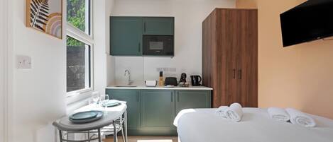 A compact bedroom with a bed, a bedside table, and a TV mounted on the wall.