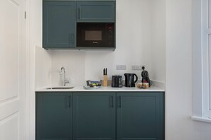 A kitchen with a microwave, sink, and cabinets. - Charmstay Westbourne PArk (London)