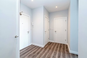 A hallway with three white doors, wooden flooring, and recessed ceiling lighting. - #94 Lux Crosby Gardens Apartment 2 beds 2 baths (Waterloo)