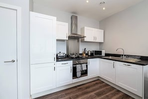 A modern kitchen with white cabinets, a stainless steel range hood, a microwave, and a sink with a dish rack. - #94 Lux Crosby Gardens Apartment 2 beds 2 baths (Waterloo)