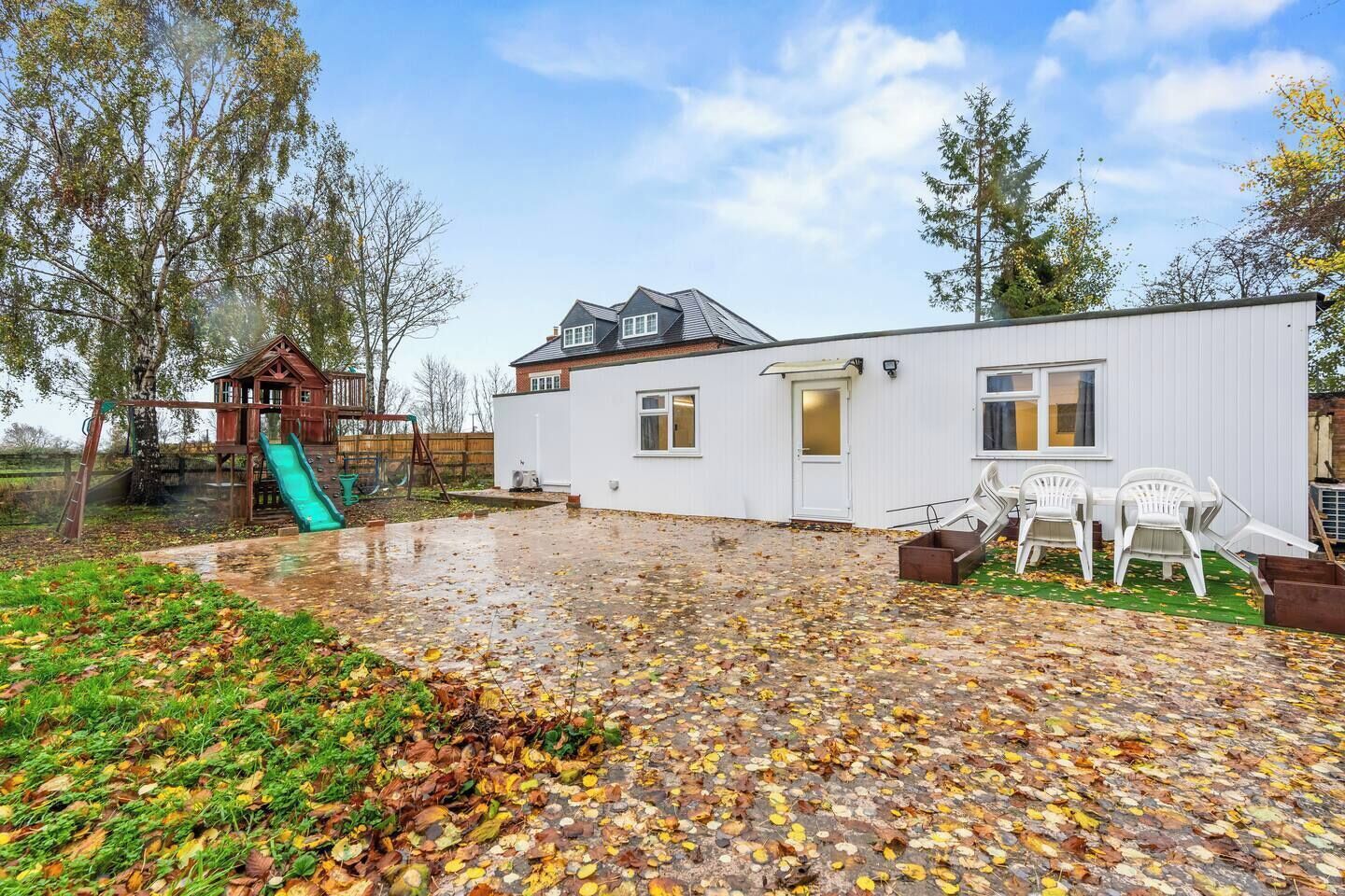 A residential property with a playhouse, a covered patio, and a white exterior wall.