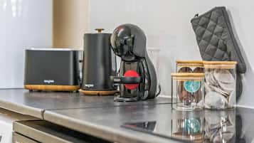 A kitchen counter with a coffee maker, a kettle, and two glass jars with lids.