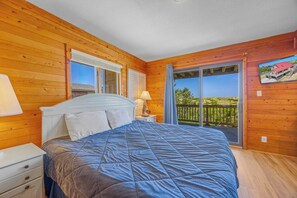 Ein Schlafzimmer mit einem Bett, Nachttischen, einem Fenster und Blick ins Freie.