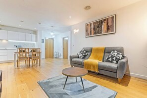 Un salon moderne comprenant un canapé, une table basse et un coin repas avec des chaises.
