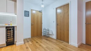 Um corredor com piso de madeira, paredes brancas e duas portas de madeira.