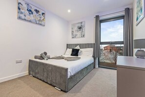 A modern bedroom with a large bed, a desk, and a view of the city. - #178 Luxury Flat in the Heart of Birmingham-for 4 (Birmingham)