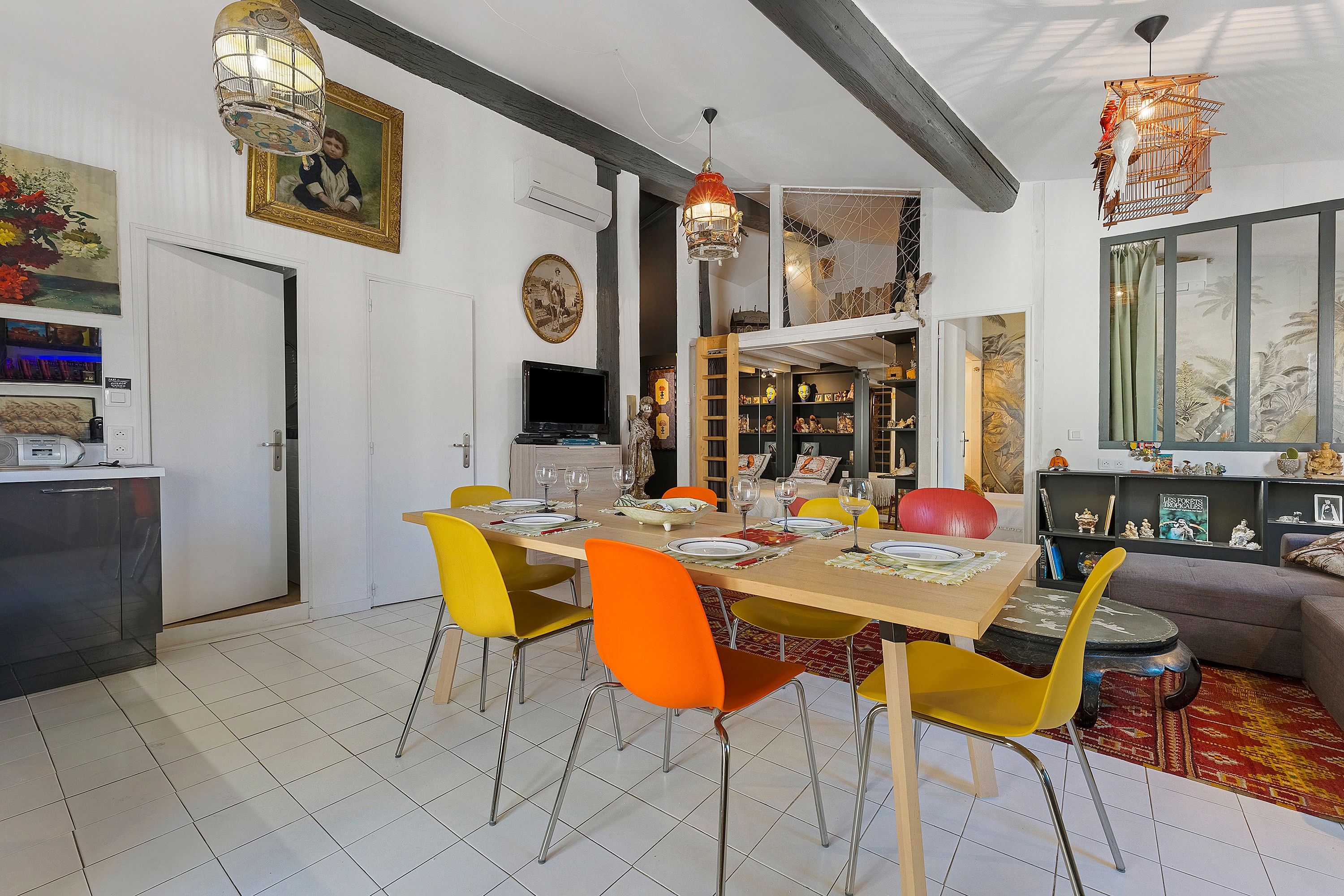 A dining area with a wooden table set for four, surrounded by chairs with yellow and orange upholstery.