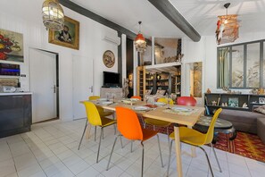 A dining area with a wooden table set for four, surrounded by chairs with yellow and orange upholstery. - City-Centre Apartment 'Les Teinturiers' with Wi-Fi (Avignon)