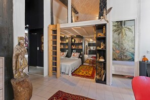 Een kamer met een bed, een ladder, een standbeeld en een boekenkast.