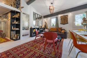 A well-lit living room with a red chair, a sofa, and a dining table set for two. - Central Apartment "Les Teinturiers" with Wi-Fi (Avignon)