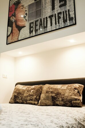 A bedroom with a bed, a wall with a large framed artwork, and a ceiling light. - Terrace & Relax | Rome Collection (Roma)