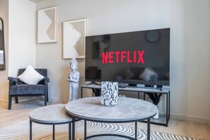 Ein modernes Wohnzimmer mit einem großen Flachbildfernseher, einer Statue, einem Sofa und einem Couchtisch.