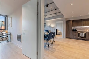 A modern interior with a dining area, kitchen, and a view of the city. - #179 Chic Birmingham City Escape - Sleeps 4 (West Midlands)