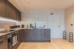 Eine moderne Küche mit Holzausstattung, einem eingebauten Backofen und einer Arbeitsfläche mit verschiedenen Geräten.
