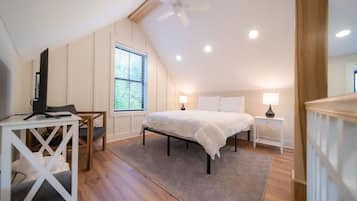 Une chambre à coucher avec un lit, des tables de chevet, un bureau et une chaise.