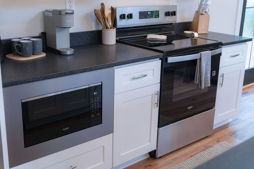 Una cocina moderna con microondas, horno y cafetera integrados.