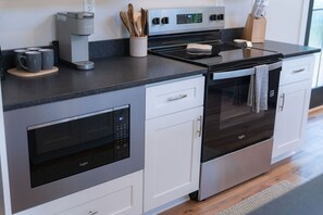 Una cocina moderna con microondas, horno y cafetera integrados.