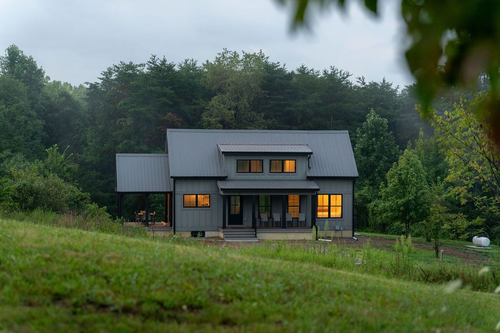 A modern two-story house with a covered porch and a small detached structure.