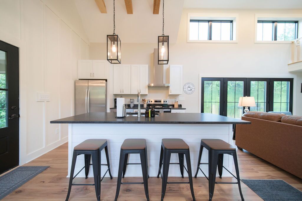 A modern kitchen with a central island, bar stools, and a dining area with a sofa.