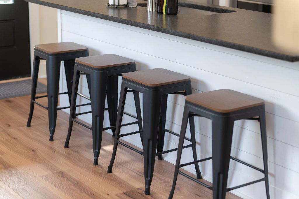 A kitchen with a black countertop and three wooden stools.