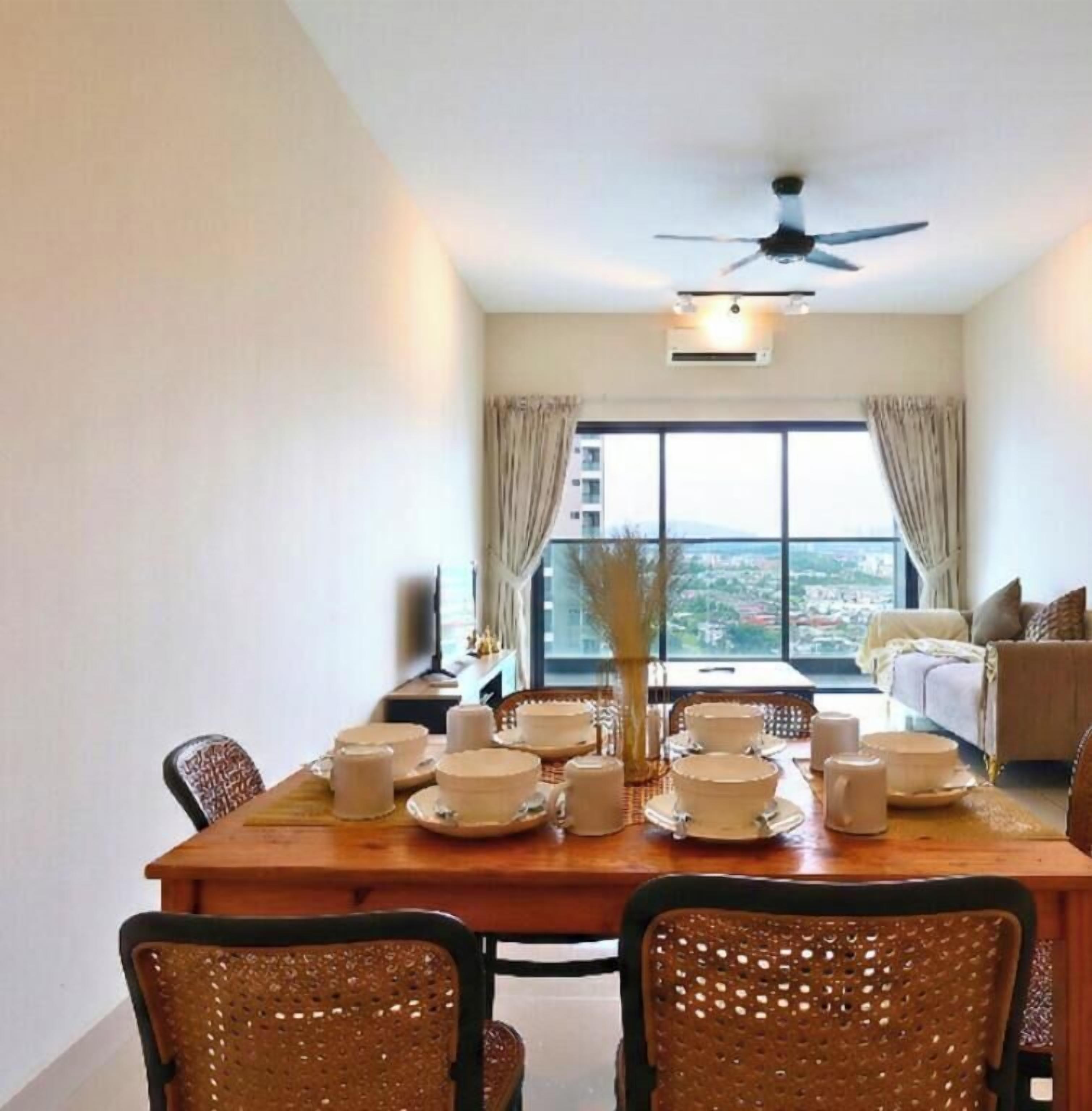 A dining area with a table set for four, a ceiling fan, and a view of a cityscape through large windows.