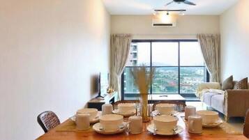 A dining area with a table set for four, a ceiling fan, and a view of a cityscape through large windows.