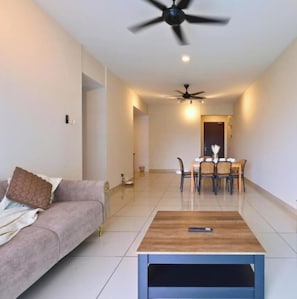 Un salon moderne comprenant un canapé, une table basse, un coin repas avec des chaises et un ventilateur de plafond.
