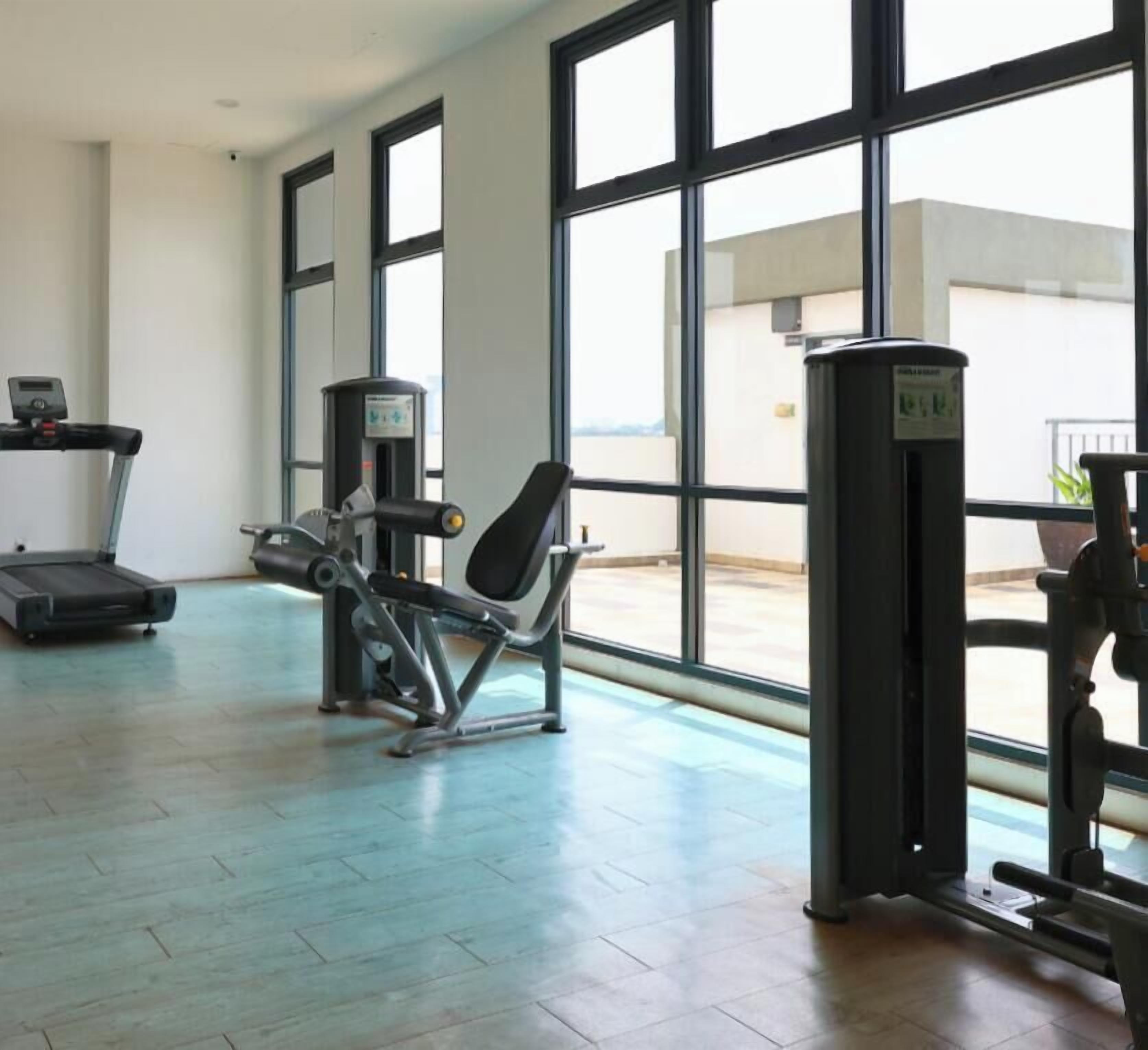 Et fitnesscenter med træningsudstyr, store vinduer og udsigt ud