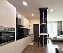 Una cocina moderna con electrodomésticos integrados, un comedor con mesa y sillas, y una sala de estar con sofá y ventana.