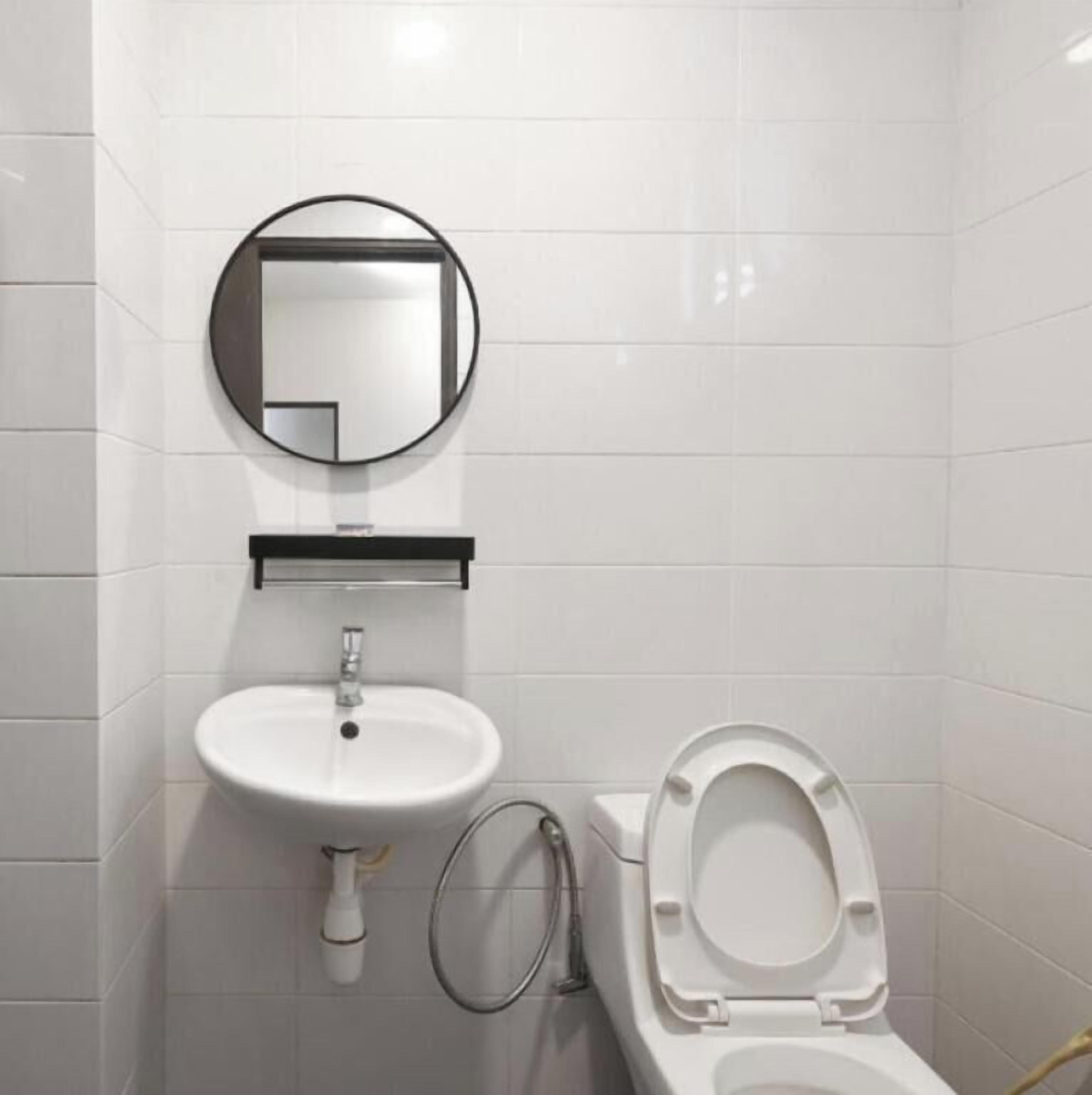 Un baño con lavamanos blanco, espejo y retrete.