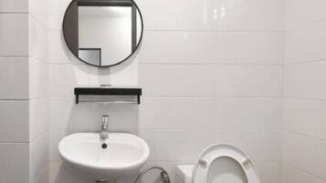 Un baño con lavamanos blanco, espejo y retrete.