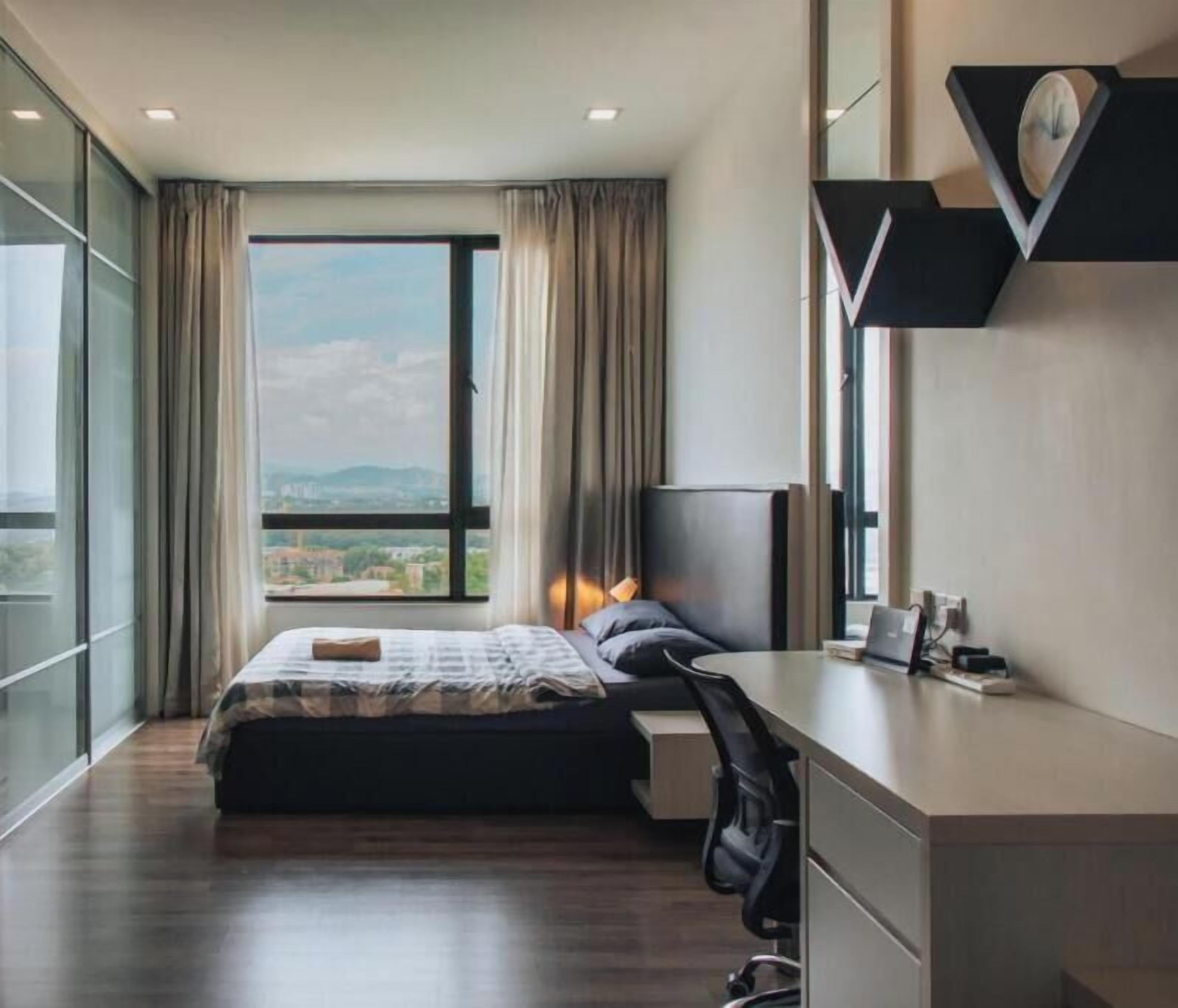 Habitación de hotel moderna con una cama grande, un escritorio, un televisor y vistas a la ciudad.